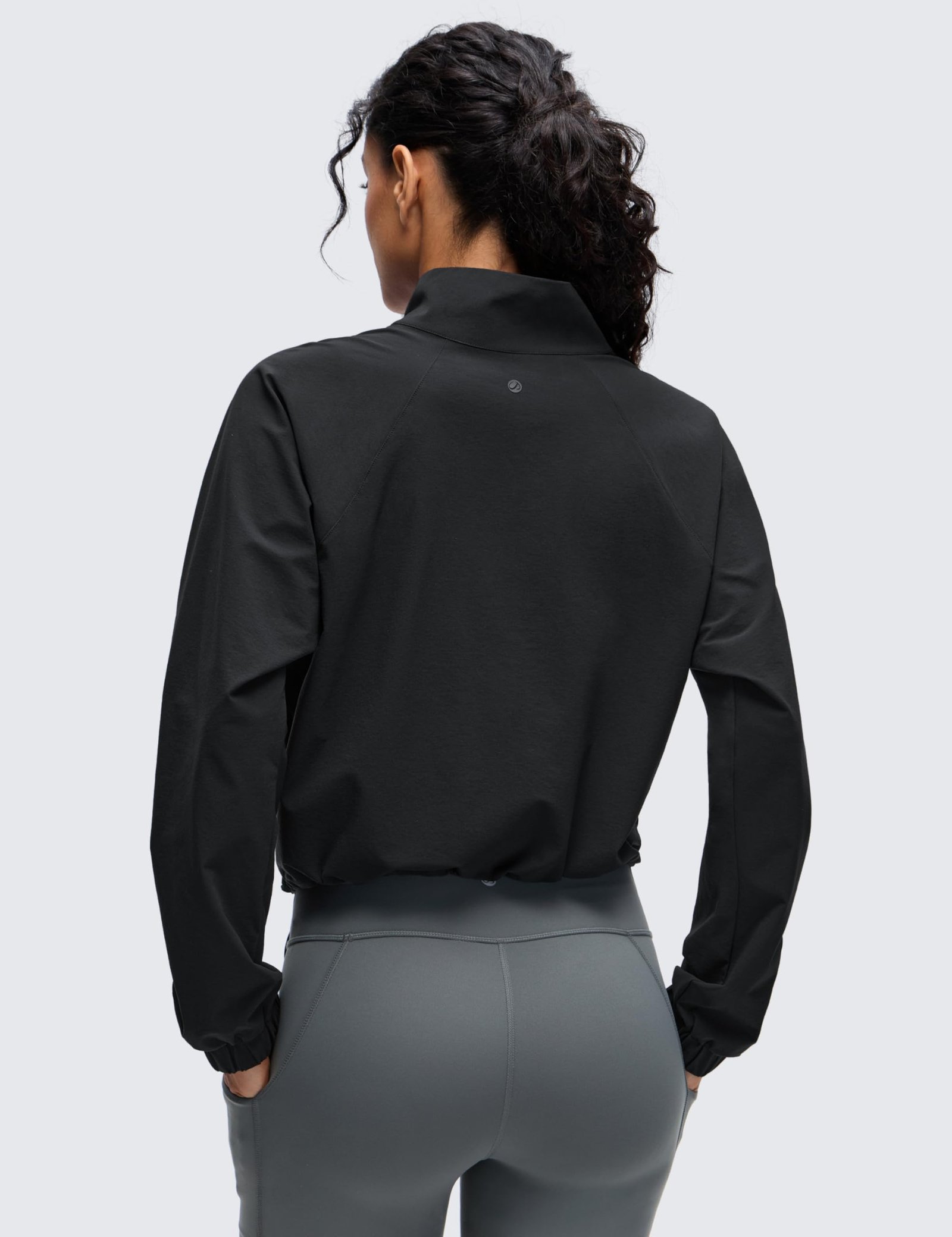 Women's black cropped half-zip jacket with stand collar, drawstring hem, elastic cuffs, and front pockets for yoga and outdoor activities