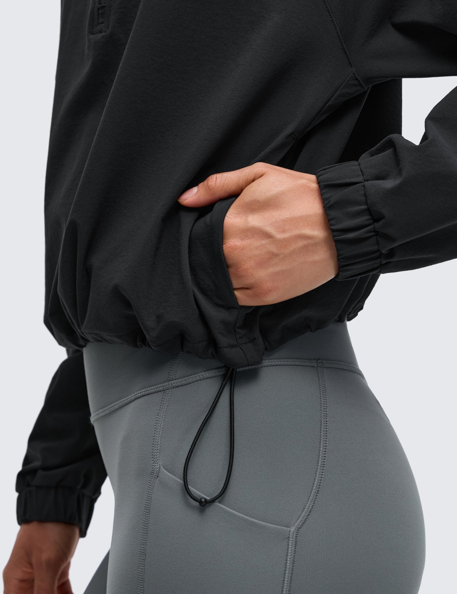 Women's black cropped half-zip jacket with stand collar, drawstring hem, elastic cuffs, and front pockets for yoga and outdoor activities