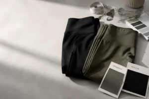 Custom yoga leggings folded with fabric swatches on design table for activewear OEM ODM manufacturing